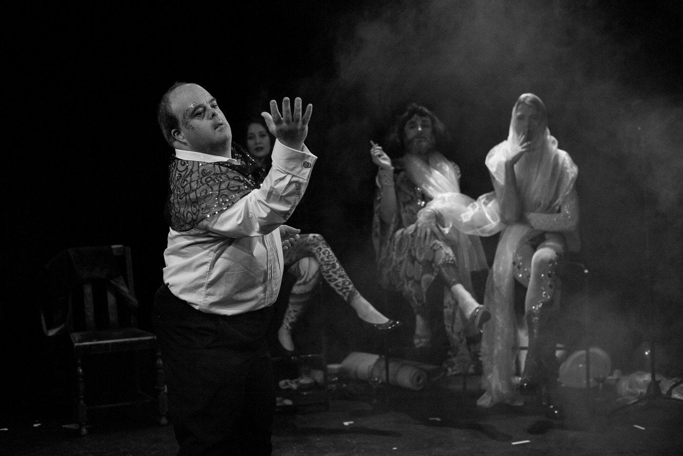 Black and white photo of Graham with arm expressively lifted and others smoking behind him